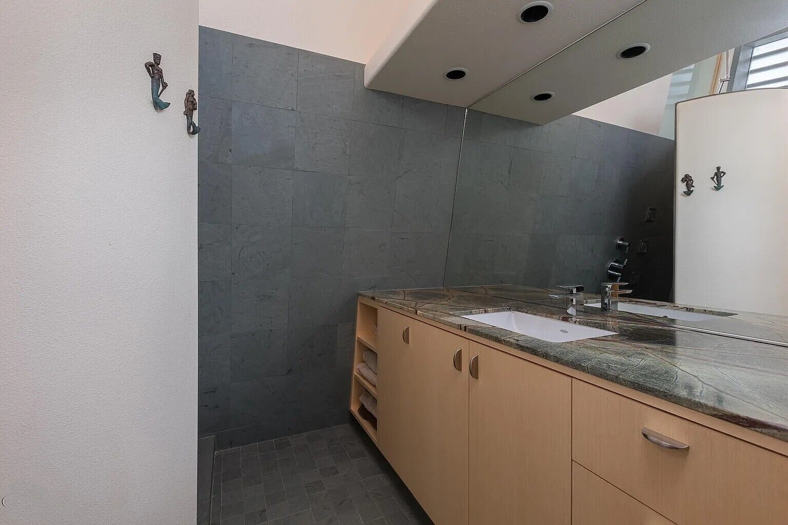A modern bathroom with a granite countertop, a white sink, and a large mirror.