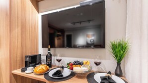 A breakfast setup with a coffee maker, wine, cheese, and fruit on a wooden table. - StayHome Allianz Park Queen Bed Varanda (São Paulo)