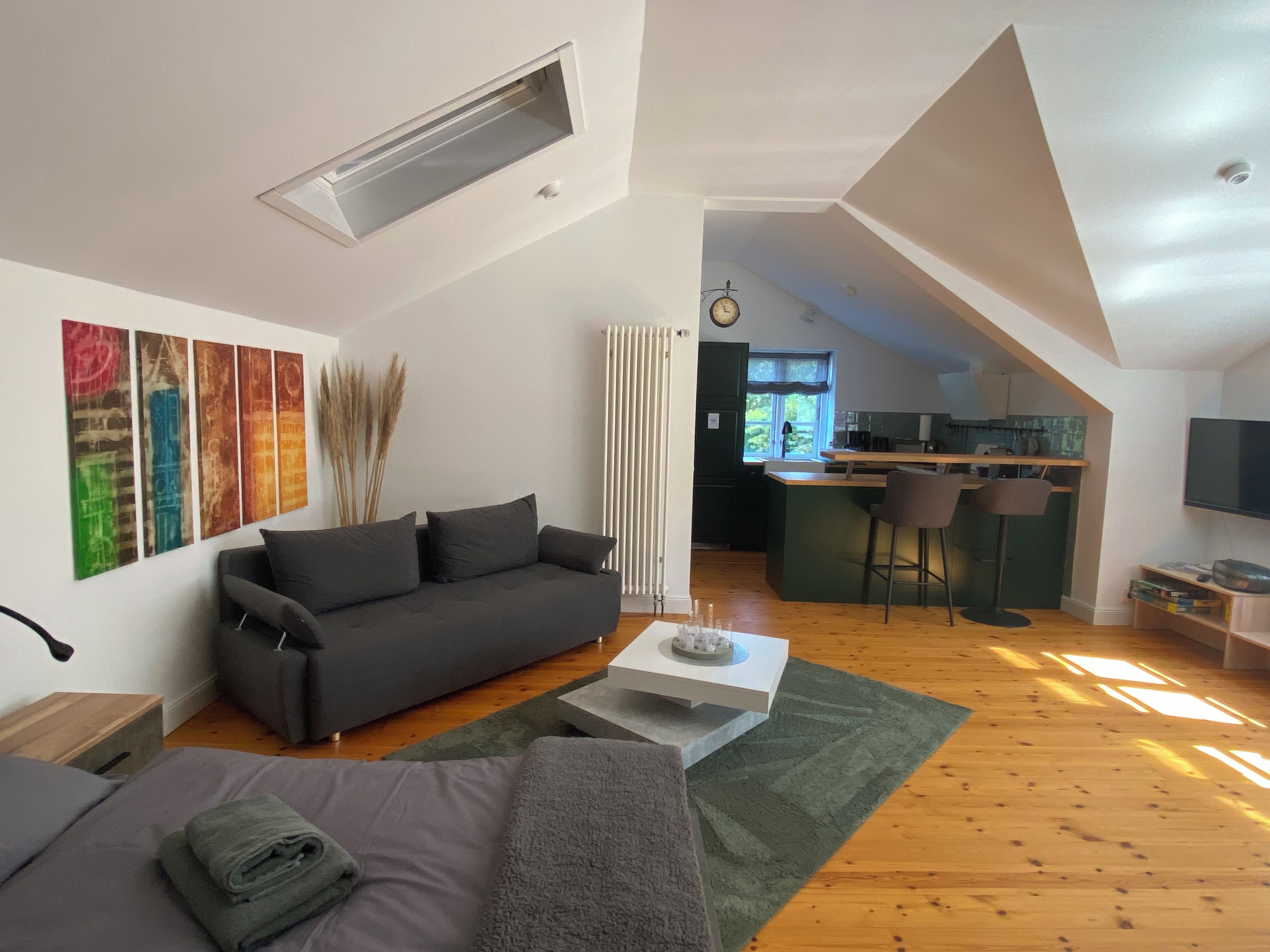 A modern loft apartment with a loft bed, a sofa, a dining area, and a kitchen.