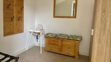 Quarto com um armário de madeira, cadeira alta e espelho na parede.