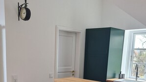 A modern kitchen with a wooden countertop, two bar stools, a black clock on the wall, and a window with a view of trees. - Arrive, relax and feel good. Idyllic location, close to the city center (Schwerin)