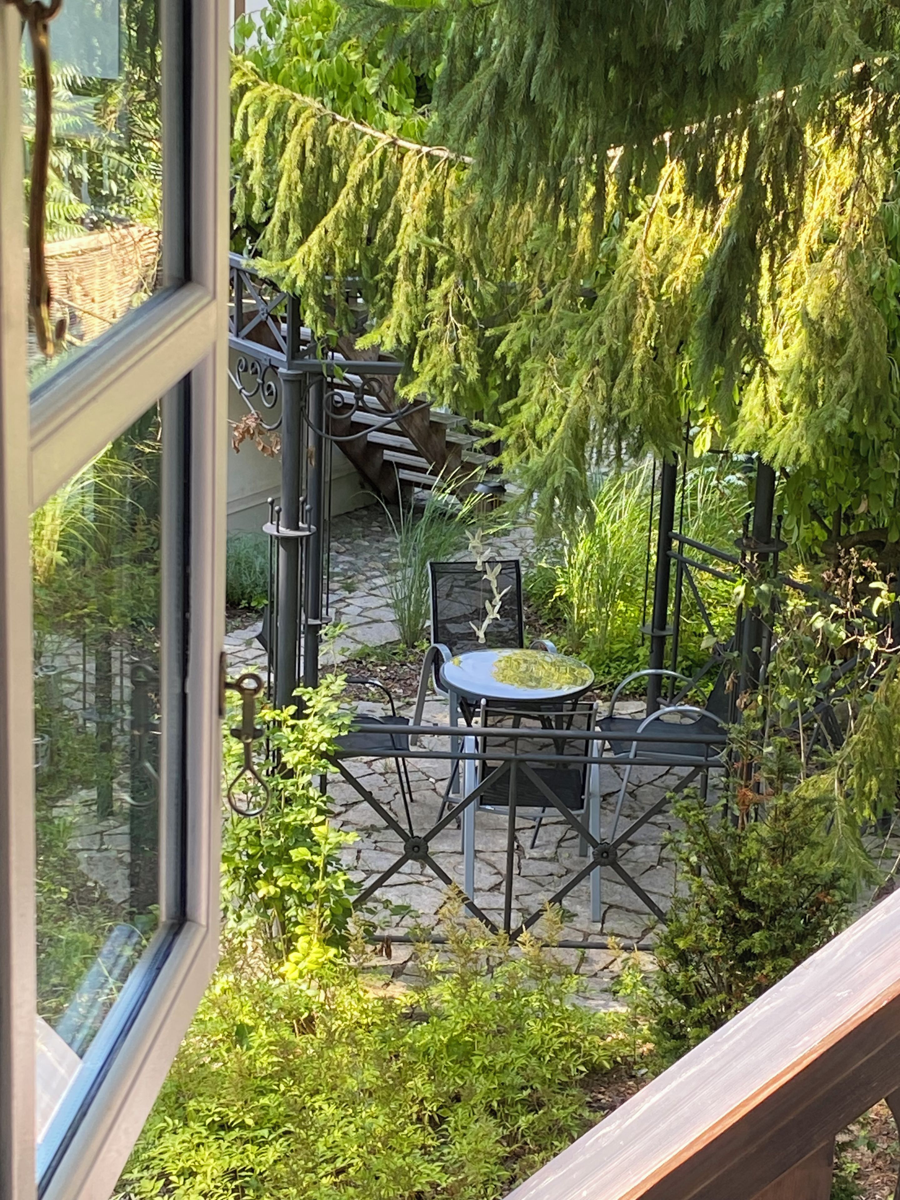 A patio area with a stone floor, a metal table and chairs, and a hanging plant.