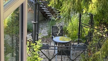 A patio area with a stone floor, a metal table and chairs, and a hanging plant.