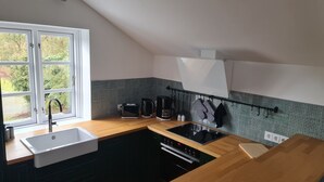 Eine Küche mit Fenster, Spüle, Herd und Kaffeemaschine.