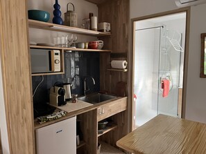 A compact kitchen with wooden cabinetry, a built-in microwave, and a sink. - Lovely studio in mas provençal with private parking (Avignon)