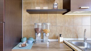 Een keuken met een houten aanrecht, twee koffieautomaten, een spoelbak en een plank met theevoorraad.