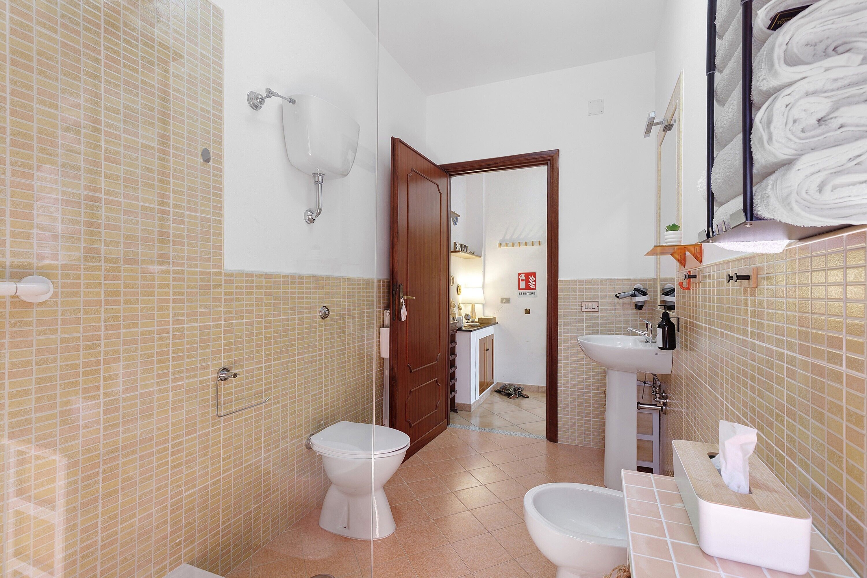Een badkamer met twee toiletten, een wastafel en een spiegel.