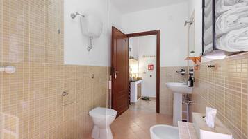 Een badkamer met twee toiletten, een wastafel en een spiegel.
