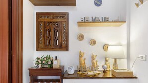 Een houten kast met een decoratieve deur, een klok, een bord met de tekst 'Welkom' en een plank met kleine spullen.
