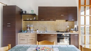 Een moderne keuken met donkere houten kastjes, een roestvrijstalen spoelbak en een eettafel met een tafelkleed met dessin.