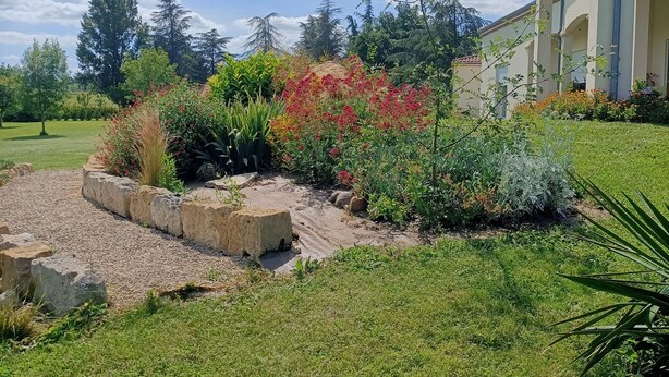 Un jardin aménagé avec une grande variété de plantes et un bâtiment orné de colonnes.