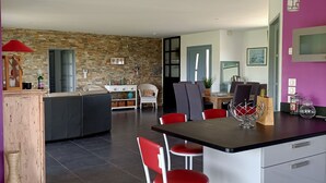 Une cuisine moderne dotée d’un îlot central, de tabourets de bar rouges et d’un coin repas avec une table et des chaises.