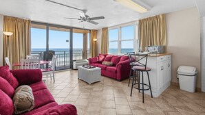 A spacious living area with a red sofa, a white cabinet, and a dining table. - Hawaiian Inn 502 (Daytona Beach Shores)