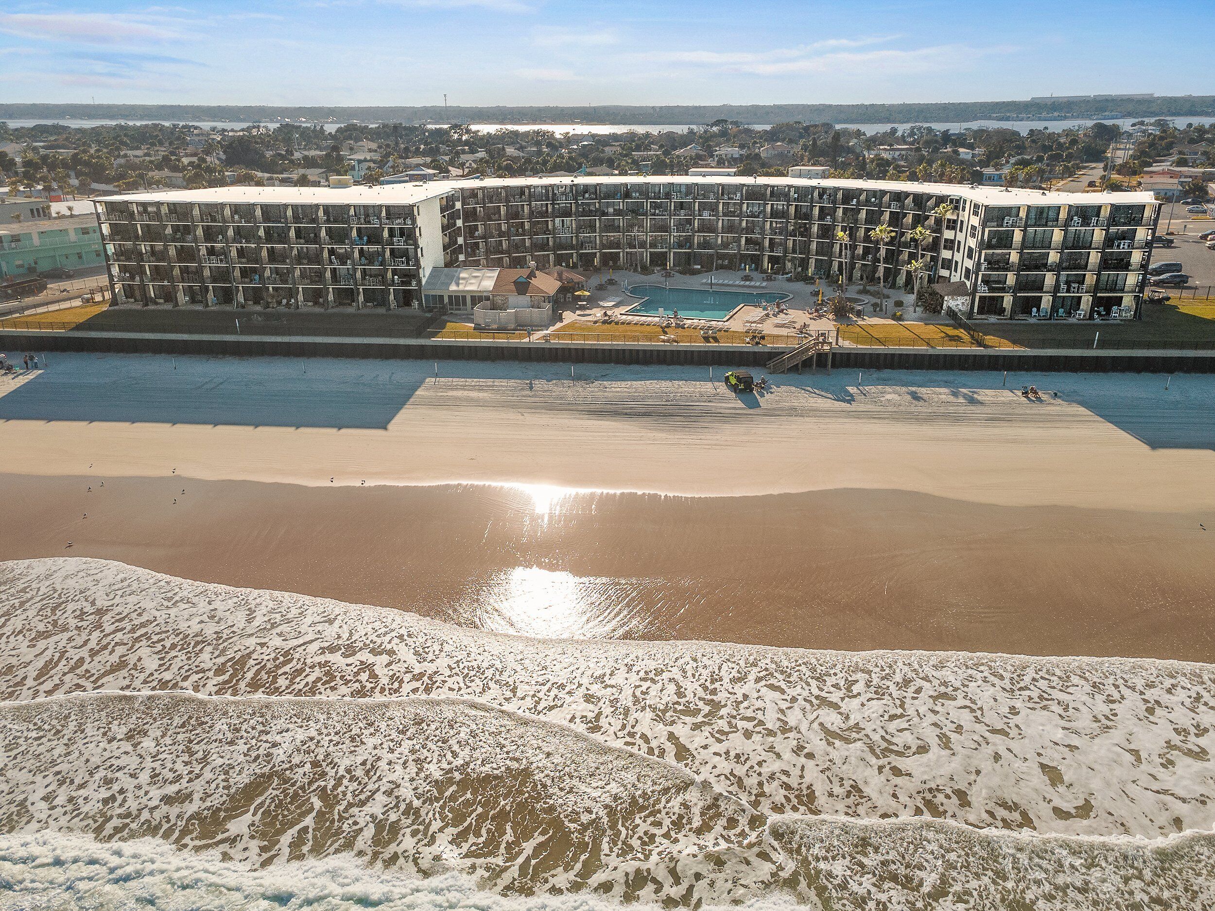Hotel moderno com piscina, praia e vista para o oceano.
