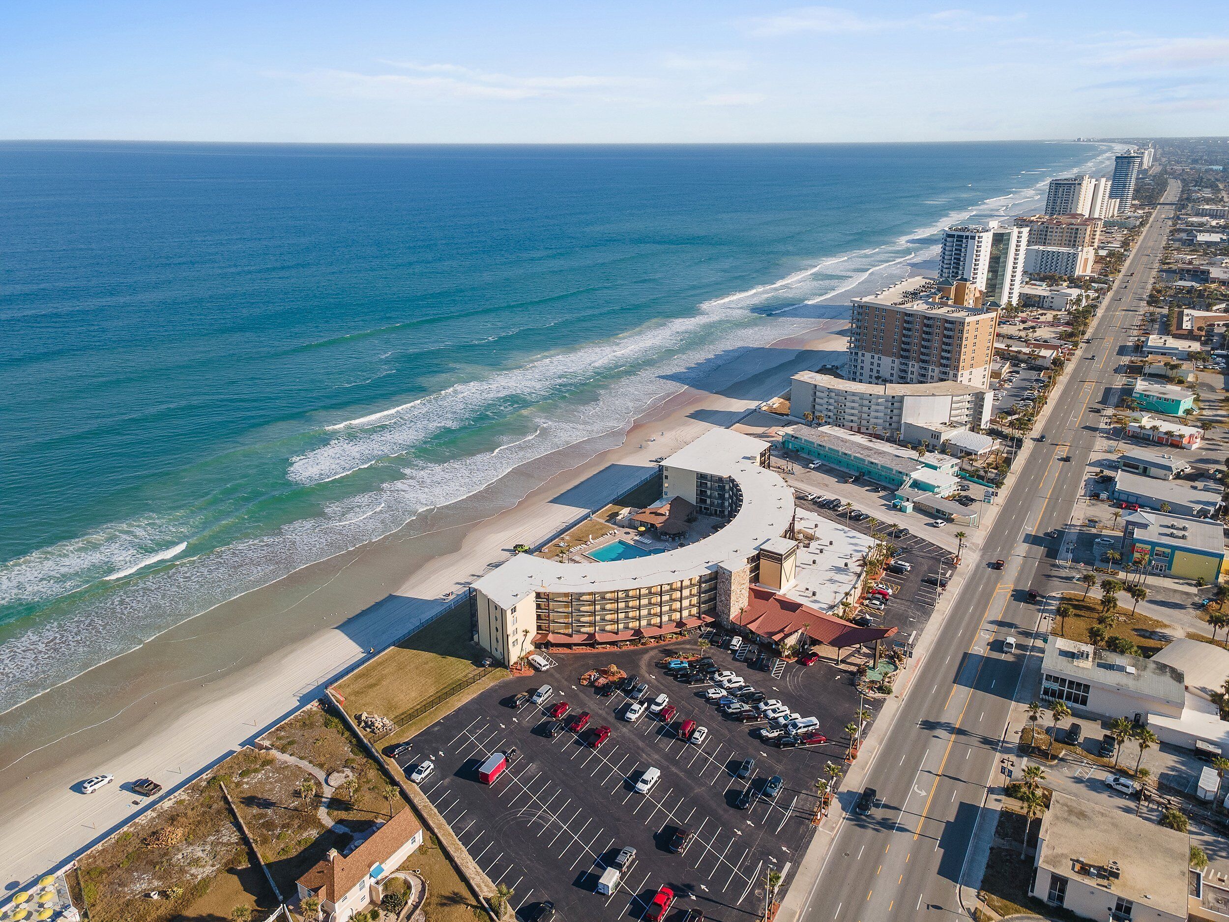Eine Luftaufnahme einer Küstenstadt mit Strand, Parkplätzen und Hochhäusern.
