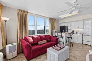 Ein modernes Wohnzimmer mit einem roten Sofa, einem weißen Korbtisch und einem Deckenventilator.