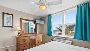 A bedroom with a bed, a dresser, a ceiling fan, a TV, and a window with curtains. - Hawaiian Inn 502 (Daytona Beach Shores)