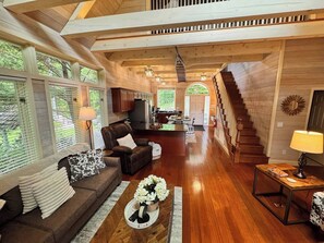 Ein großzügiger Wohnbereich mit Holzboden, einer Sofagarnitur, einem Couchtisch und einer Treppe, die in eine obere Etage führt.