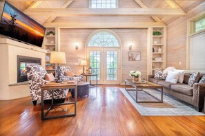 A spacious living room with a fireplace, a large TV, and a cozy seating area with a couch and chairs. - Mountain View Hideaway | Hot Tub + EV Charger (Pigeon Forge)