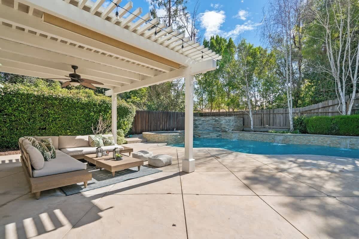 A covered patio with a pool, outdoor furniture, and a pergola.