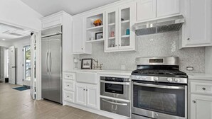 Uma cozinha moderna com armários brancos, eletrodomésticos de aço inoxidável e painel de azulejos.