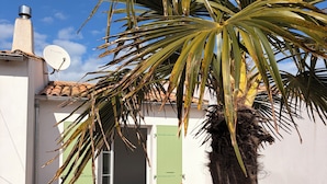 A house with a satellite dish, a bed with a green door, and a red chair. - L'ARS DE VIVRE – Exceptional Home in Ars-en-Ré | Pool | Sleeps 10 (Ars-en-Ré)