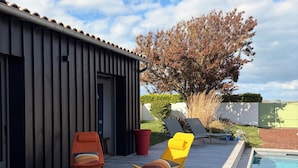 A wooden deck with a pool, lounge chairs, and a small table. - L'ARS DE VIVRE – Exceptional Home in Ars-en-Ré | Pool | Sleeps 10 (Ars-en-Ré)