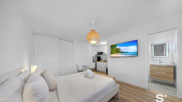 A modern hotel room with a bed, a TV, a bathroom, and a kitchenette. - Chic Miami Studio - Gym and Free Parking (North Miami)