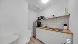 A compact kitchen with white cabinets, a wooden countertop, a microwave, a coffee maker, and a small dining table with a chair. - Chic Miami Studio - Gym and Free Parking (North Miami)
