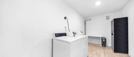 A compact laundry room with a washing machine, a drying rack, and a small trash bin.