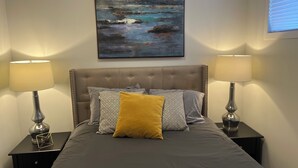 Un dormitorio con cama, dos lámparas de noche, una mesita de noche y un cuadro en la pared.
