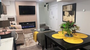 Una sala de estar moderna con chimenea, televisor de pantalla plana, mesa de comedor con individuales amarillos y un sofá.