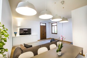 Una sala de estar moderna con sofá, mesa de comedor y lámparas colgantes.