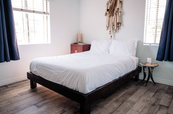 Une chambre à coucher avec un lit en bois, une petite table de chevet et un élément décoratif fixé au mur.
