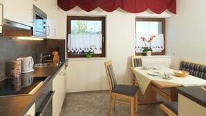 Une cuisine compacte équipée d’un four à micro-ondes, d’une cuisinière et d’un coin repas avec un banc et une table.
