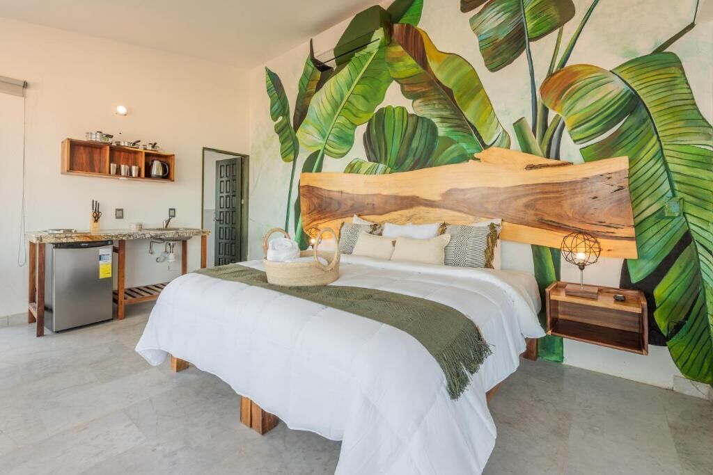 A bedroom with a bed, a nightstand, a wall-mounted shelf, a small refrigerator, and a door.