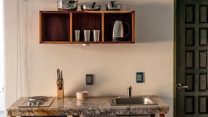 A kitchen with a marble countertop, a built-in shelf above the sink, and a green door. - La Casa Blanca (Puerto Vallarta)
