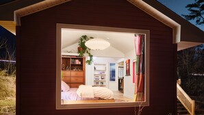 Une chambre confortable avec un lit, une commode en bois, une bibliothèque et une plante suspendue.