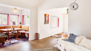 Une pièce spacieuse avec un banc en bois, un canapé moelleux et un coin repas comprenant une table et des chaises.