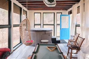 Une piĂšce avec un jacuzzi, un fauteuil suspendu, une table de billard et une porte bleue.