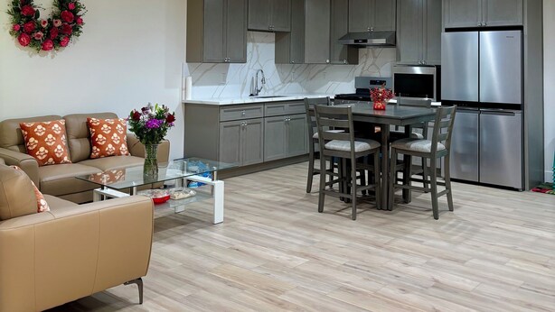 Een moderne woonkamer met een bank, salontafel en een eethoek met stoelen.