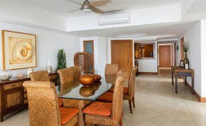 A dining area with a glass table, wicker chairs, and a ceiling fan. - Luxury 3-Bedroom Beachfront Condo | Bay View Grand Ixtapa (Ixtapa Zihuatanejo)