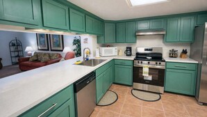A kitchen with teal cabinets, a stainless steel oven, and a white countertop. - Renovated 1st Floor Beach 250ft Pool (South Padre Island)