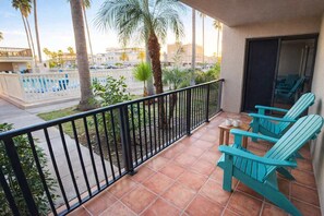 A balcony with a view of a pool, palm trees, and a cityscape. - Renovated 1st Floor Beach 250ft Pool (South Padre Island)