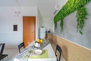 Un comedor con una mesa dispuesta para dos personas, un refrigerador y un microondas al fondo.