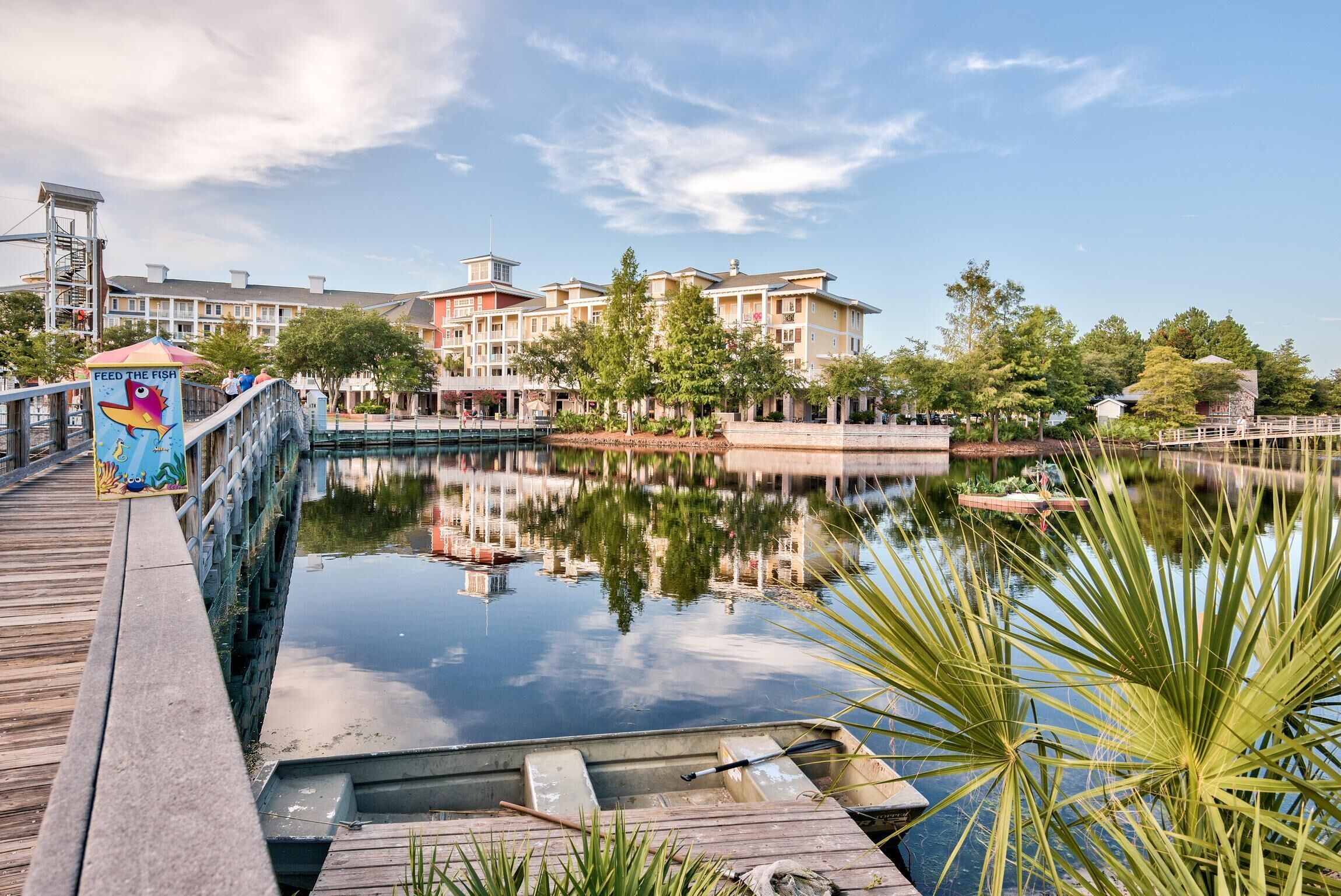 A waterfront hotel with a wooden deck, a bridge, and a reflection pool.