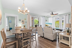 A dining area with a wooden table and chairs, a chandelier, and a ceiling fan. - Market Street Inn 248- Beauty by the Bay (Miramar Beach)