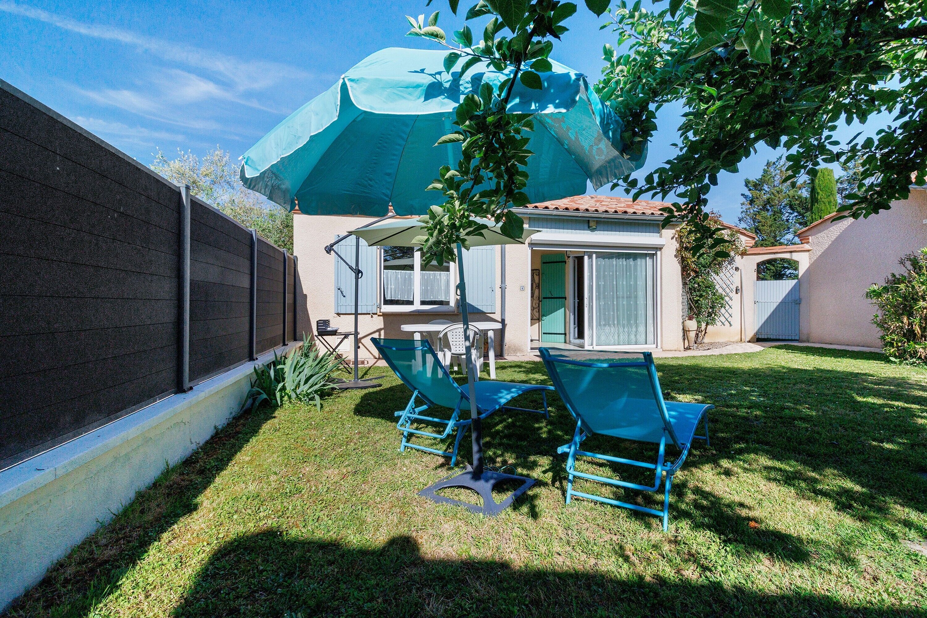 A backyard with a patio, two blue chairs, a table, and a large blue umbrella.