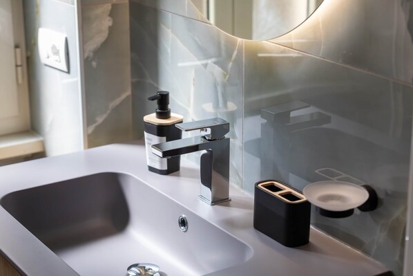 A modern bathroom with a sleek sink, a black soap dispenser, and a mirror. - Maya Casa Rosso - Premium Studio in Central Rome (Rome)