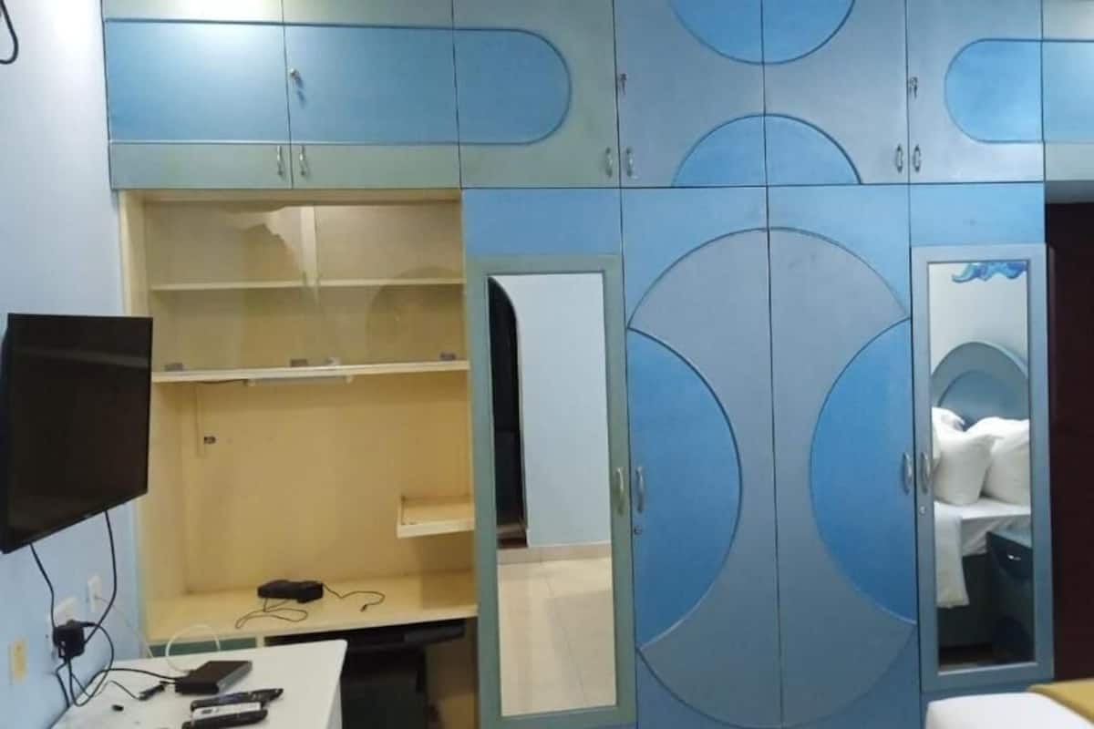 Ein Schlafzimmer mit einem Bett, einem Schreibtisch mit Computer und einem Kleiderschrank mit Rundmustern.